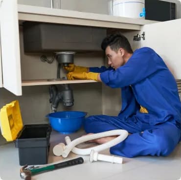 Plumber fixing a leak under a kitchen sink